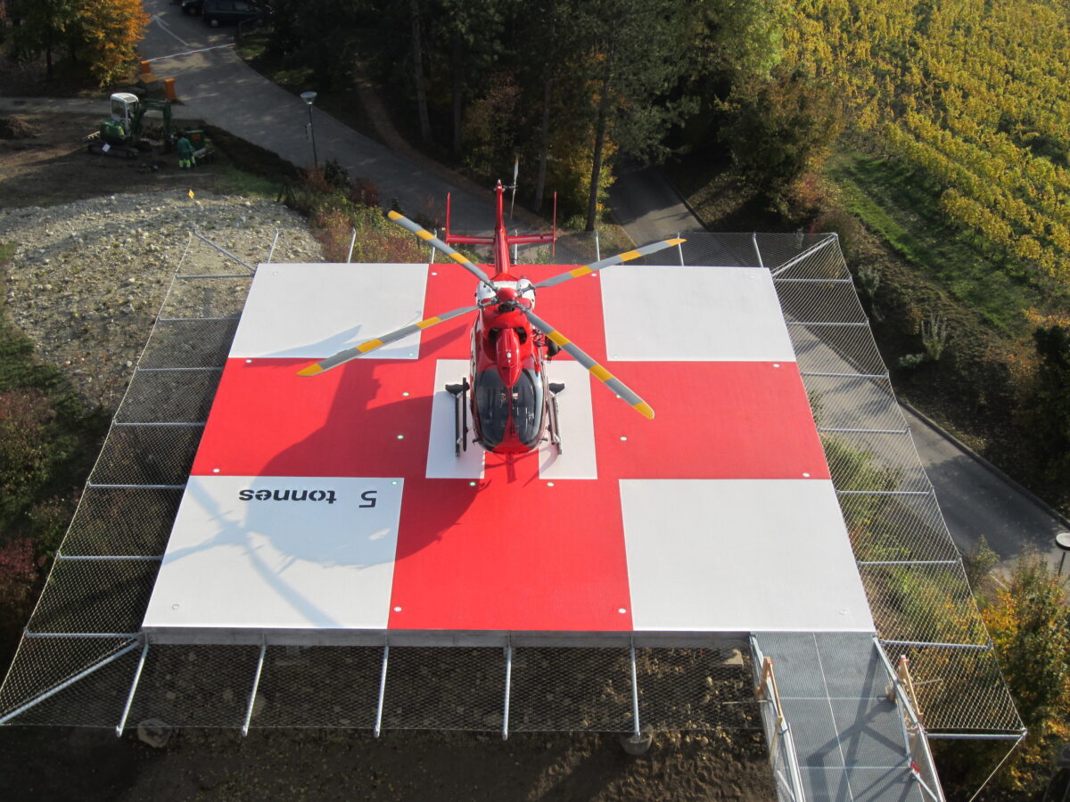 Helicopter landed on a red and white heliport.