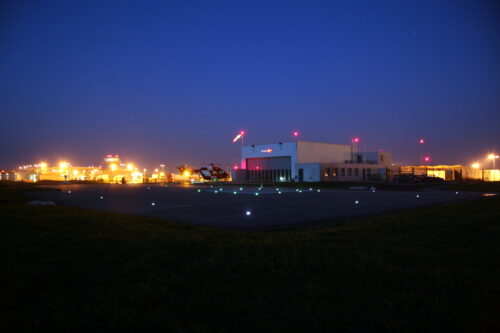Helipad in night with helicopter and hangar